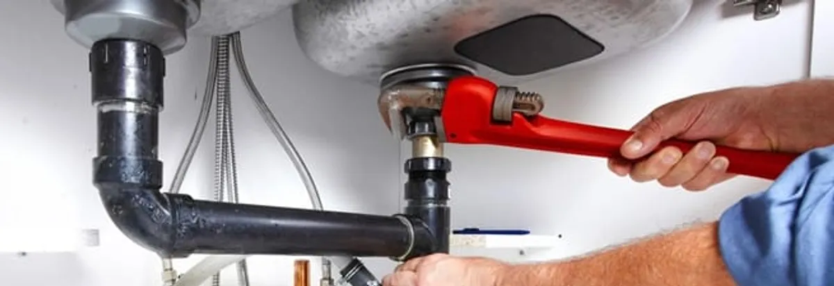Garbage disposal repair technician tightening the sink drain and disposal connection in Detroit, MI