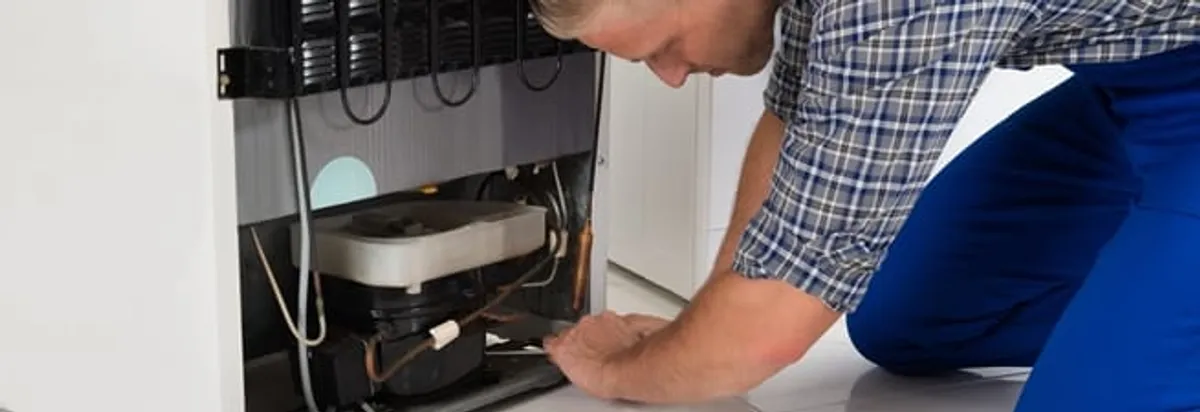 Refrigerator repair technician servicing the compressor and condenser area in Detroit, MI