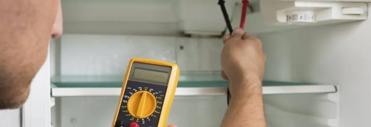 Refrigerator repair technician testing electrical components with a multimeter in Detroit, MI