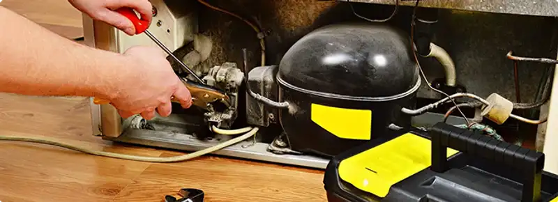 Refrigerator repair technician fixing the compressor and wiring in Detroit, MI